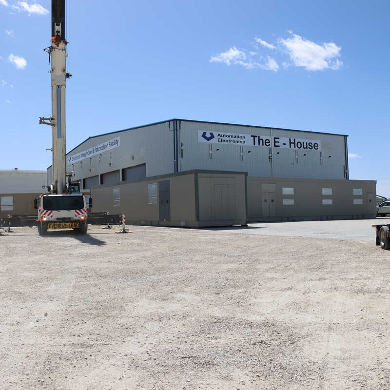 A crane loading a power distribution skid onto a truck for shipment to a job site.